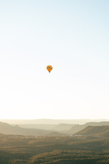 Vertical image of wide shot of hot air balloon isolated against white sky background in early morning flight.
