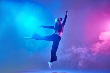 a girl in dark clothes dances on a neon background in smoke, modern dance