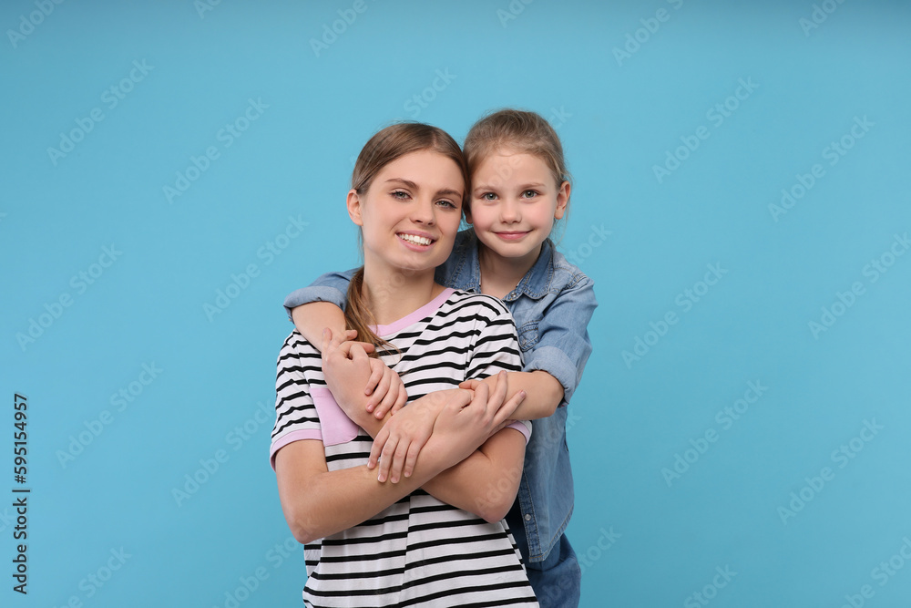 Sticker Little daughter hugging her mom on light blue background. Happy Mother's Day