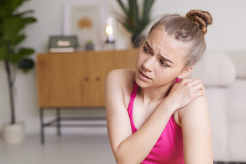 girl in bright sportswear at home shoulder pain