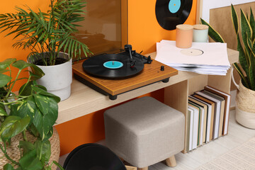 Stylish turntable with vinyl record on console table in cozy room