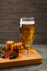 Glass of beer, delicious fried steak and corn on grey table