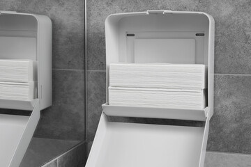 New open paper towel dispenser hanging on wall near mirror in bathroom