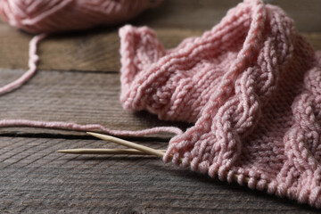 Pink knitting and needles on wooden table, closeup