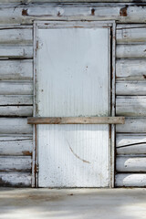 An image of a old wooden door barred closed by a piece of board across the doorway. 