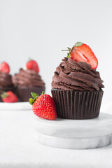 Chocolate cupcake with dark chocolate buttercream and strawberries, double chocolate cupcakes with american buttercream, tall swirl frosting on a cupcake with a strawberry