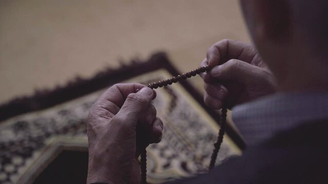 Muslim man hand holding prayer beads, hands in prayer rope, brown rosary beads
