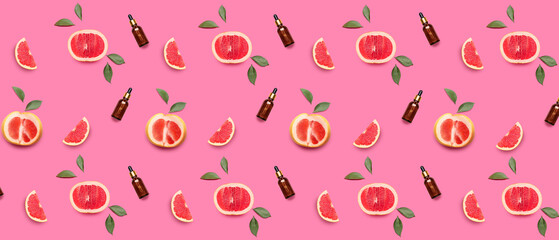 Many bottles of grapefruit essential oil on pink background. Pattern for design