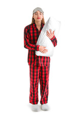 Young woman in checkered pajamas with pillow on white background