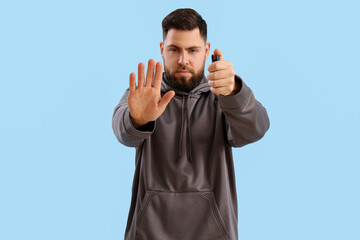 Naklejka premium Young man with pepper spray for self-defence on blue background