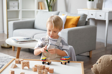 Fototapeta na wymiar Cute little boy playing with wooden toys at home