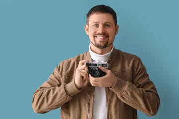 Male photographer with camera on blue background