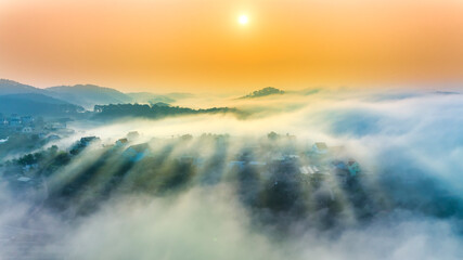Fototapeta premium Aerial view of Xuan Tho suburbs near Da Lat city at morning with misty and sunrise sky. This place is considered most beautiful and peaceful place to watch sunrise in highlands of Vietnam