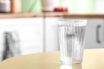 Glass of water on wooden table in kitchen, closeup
