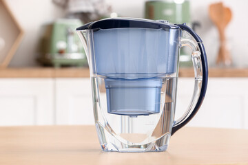 Modern filter jug on wooden table in kitchen