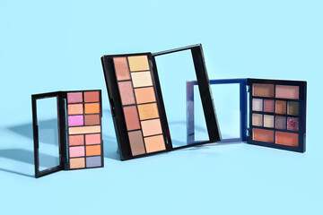 Palettes of beautiful eyeshadows on color background