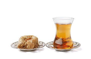 Plate with tasty baklava and glass of Turkish tea on white background