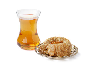 Plate with tasty baklava and glass of Turkish tea on white background