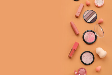 Decorative cosmetics with sponges on orange background