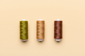 Three thread spools on color background