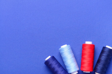 Set of different thread spools on blue background