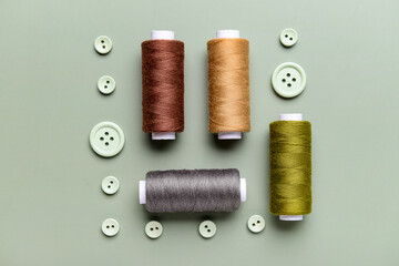 Composition with thread spools and buttons on grey background