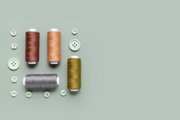 Composition with thread spools and buttons on grey background