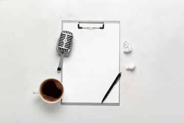 Clipboard with microphone, cup of coffee and crumpled paper on white background