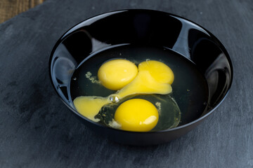 Homemade chicken eggs with yellow yolk broken in a bowl