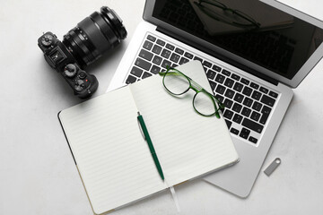 Notebook with eyeglasses, laptop and photo camera on white background - obrazy, fototapety, plakaty