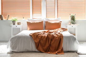 Interior of light bedroom with big bed, tables and window