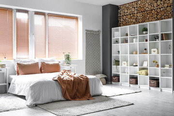 Interior of light bedroom with tables and shelving unit