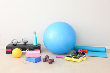 Sports equipment with sneakers near light wall in gym