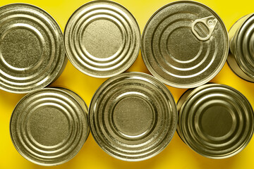 Assortment of tin cans with fish on yellow background, closeup