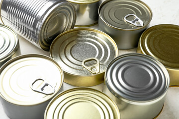 Assortment of tin cans with fish on white table, closeup