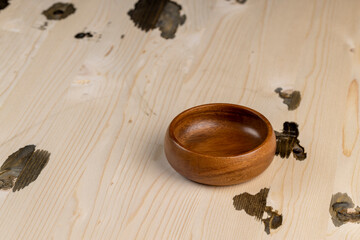 an empty wooden bowl of dark color on a white board