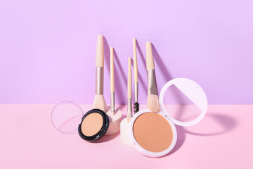 Decorative plaster podiums, powder and brushes on lilac background