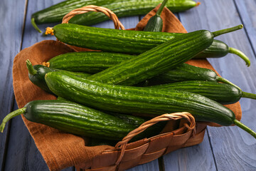 Basket with fresh cucumbers on grey wooden background