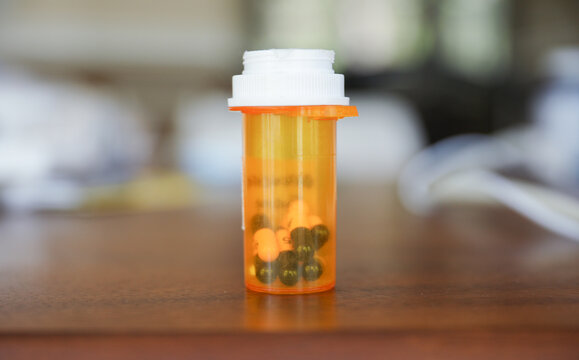 round orange bottle filled with pills representing medicine and health. Symbolizes healing, treatment, and relief from illness or pain