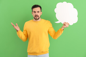 Angry young man with blank speech bubble on green background