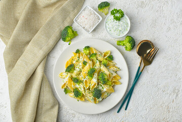 Plate with tasty pasta and broccoli on light grunge background