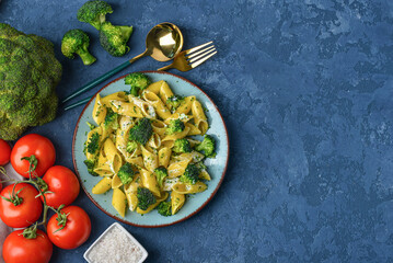 Plate with tasty pasta and broccoli on blue background