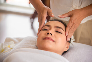 Fototapeta na wymiar Professional masseuse doing head massage beautiful asian woman with close up shot in spa room.