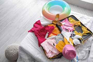 Open suitcase with beach accessories on bed in room