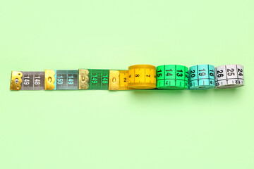 Colorful measuring tapes on green background