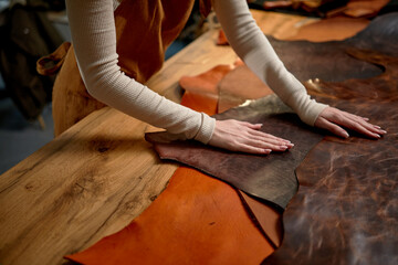female hands cleaning the surface of leather, close up cropped side view shot. craftswoman smoothes...