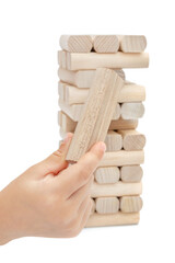 Child hand holding wooden brick against falling wooden tower on white. Playing game.