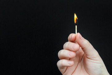 Hands holding burning match on black background. Copy space. - 595187152