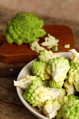 Bowl with baby romanesco cabbage on wooden table