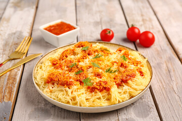 Plate of tasty Italian pasta with Parmesan cheese on light wooden background